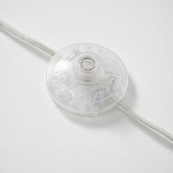 Clear plastic inline power switch on white background.