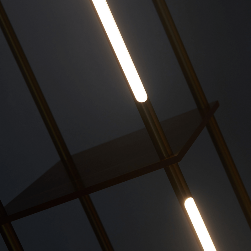 Close-up of modern arched brass floor lamp with warm white LED tube lights and glass shelf, contemporary minimalist living room lighting