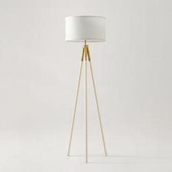 Modern tripod floor lamp with white drum shade and brass gold accents on neutral background, minimalist Scandinavian living room lighting