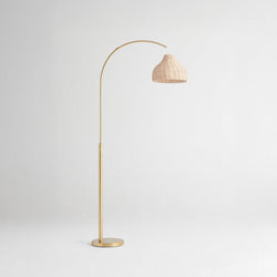 Gold floor lamp with rattan shade on a light background.