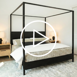 Black canopy bed in a bedroom setting with a play button overlay