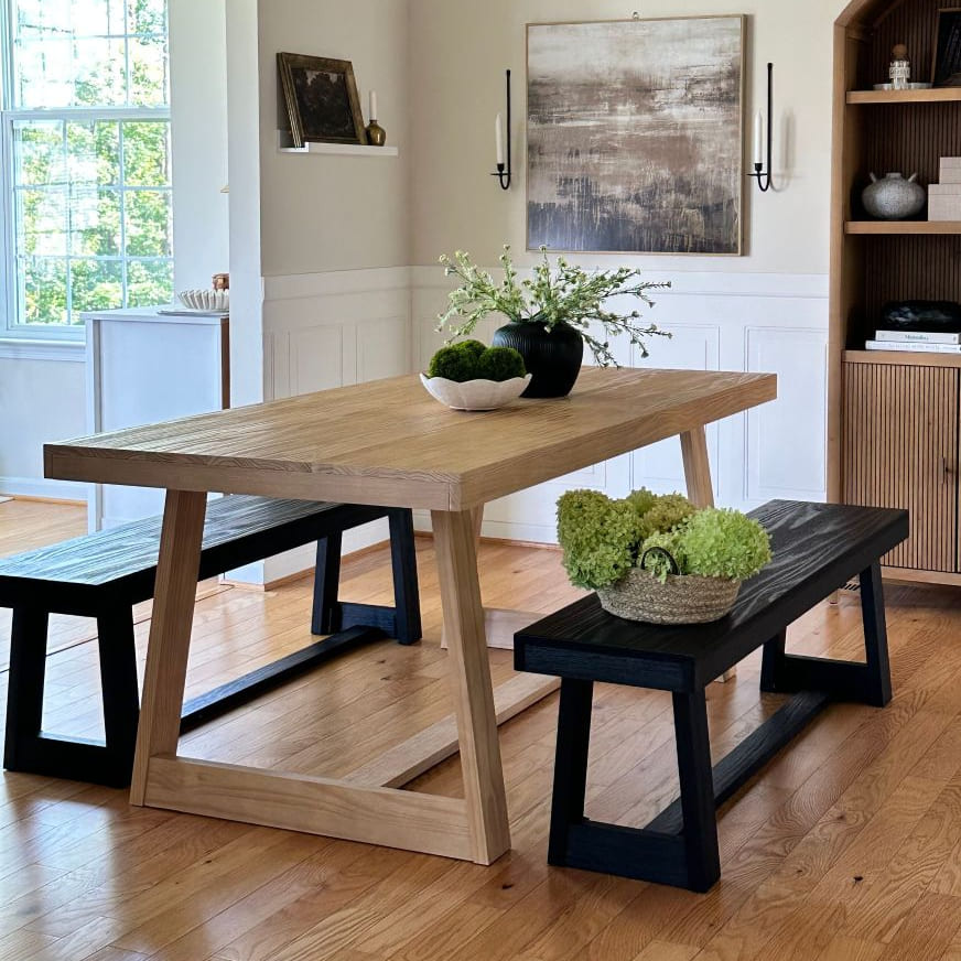 Dark wooden coffee table with decorative items including a plant, books, and a candle in a living room setting.