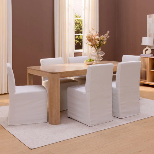 Dining room with a wooden table and white chairs in a well-lit room.