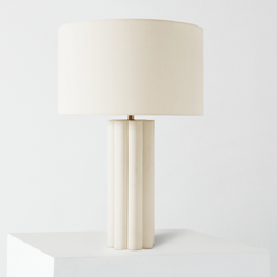 Minimalist white ceramic table lamp with fluted column base and cream drum shade on pedestal, modern bedside lighting