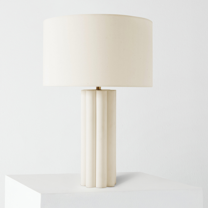 Minimalist white ceramic table lamp with fluted column base and cream drum shade on pedestal, modern bedside lighting