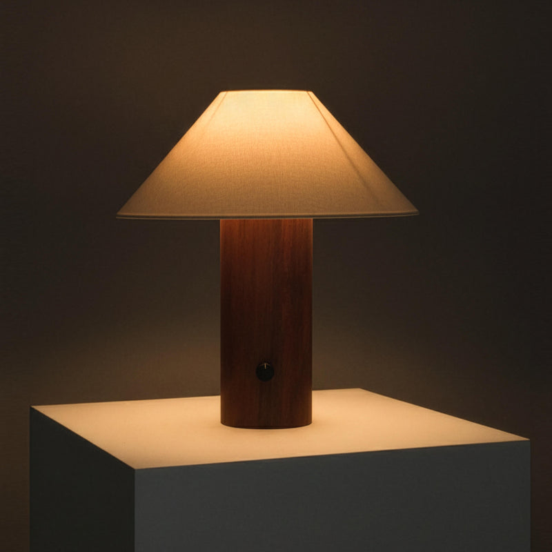 Minimalist wooden table lamp with beige fabric lampshade on a white pedestal, warm ambient lighting ideal for bedroom or living room
