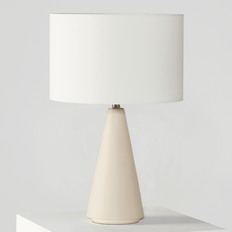 Modern cone-shaped table lamp with white shade on a minimalist white surface.