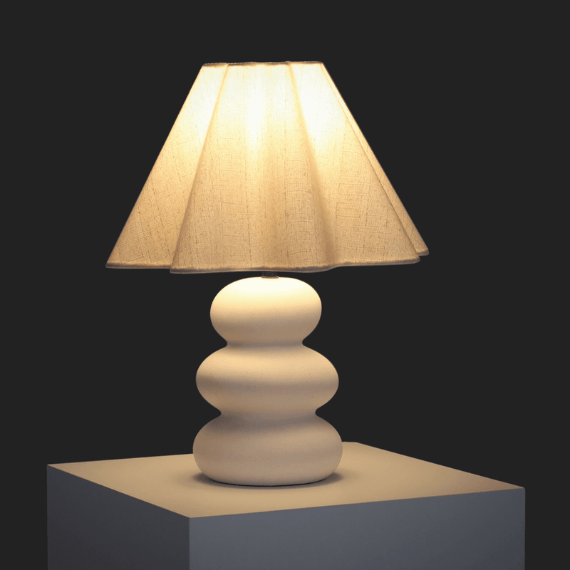 Elegant modern table lamp with a textured white base and beige fabric lampshade, perfect for contemporary home decor.