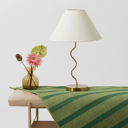 Elegant table setting with a modern gold lamp and flower vase on a striped green table runner.
