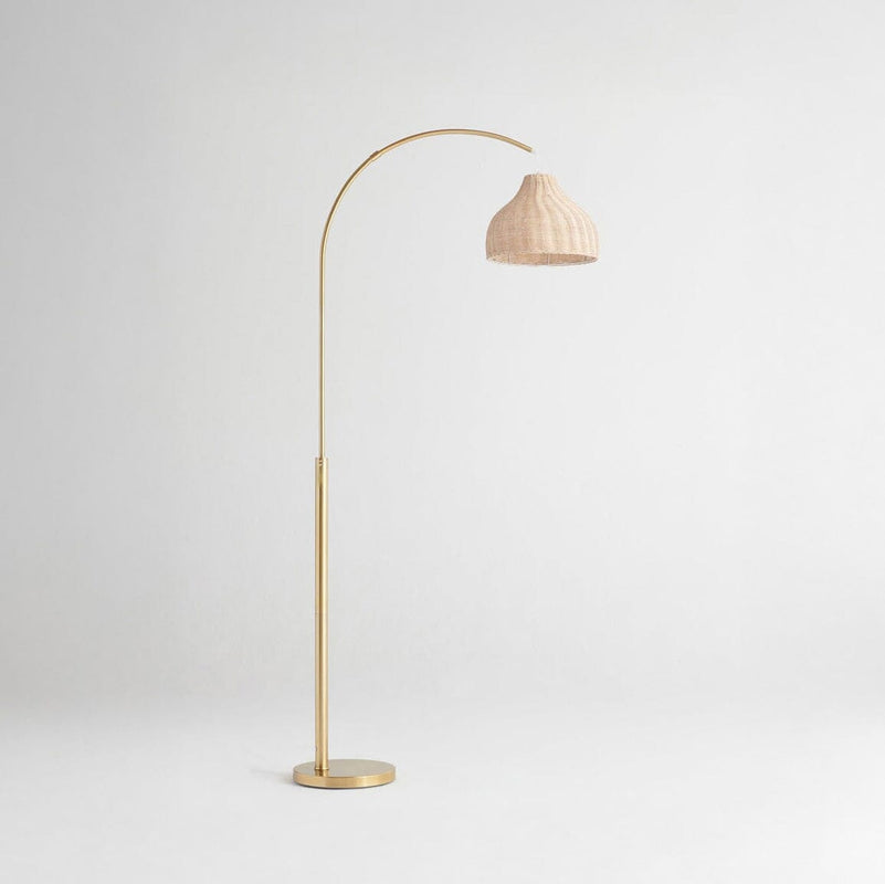 Gold floor lamp with rattan shade on a light background.