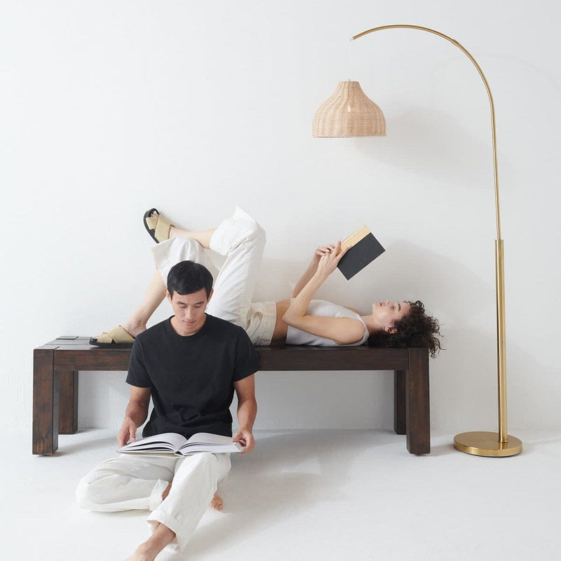 Two people relaxing and reading books under a stylish floor lamp in a modern minimalist living room.
