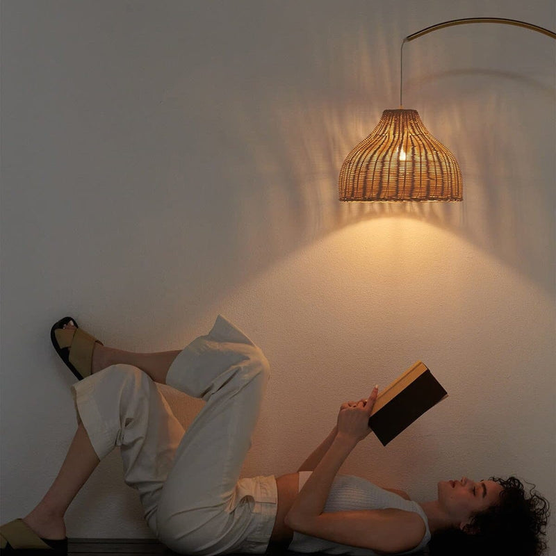 Young woman relaxing and reading a book under an elegant rattan wall lamp.