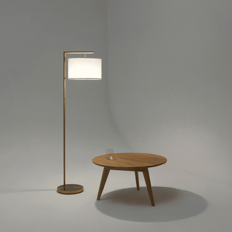 Modern wooden coffee table with a glass of water next to a sleek floor lamp on a minimalistic white background.