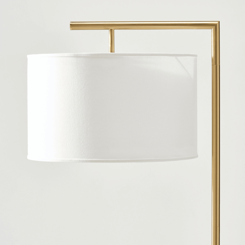 Modern gold floor lamp with white drum shade.