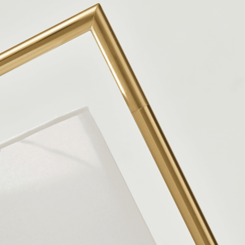 Close-up of a modern gold frame on a white fabric background.