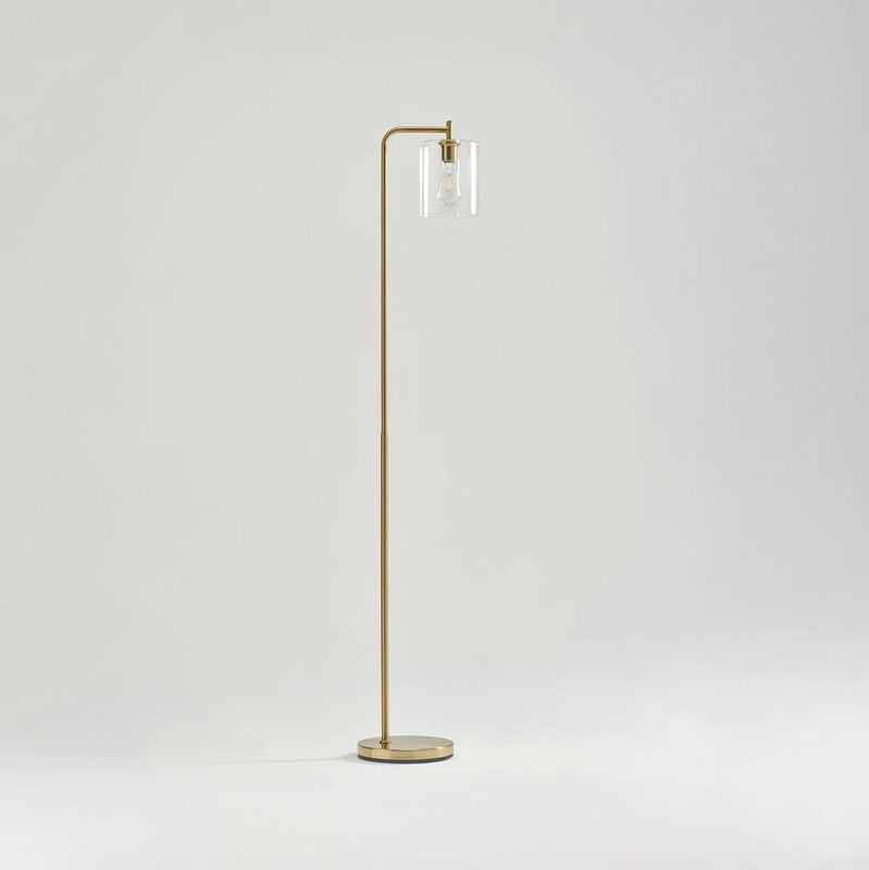 Modern gold floor lamp with clear glass lampshade on minimalist white background.