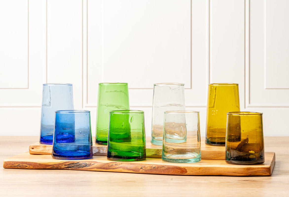 Colorful recycled glass tumblers on a wooden tray.