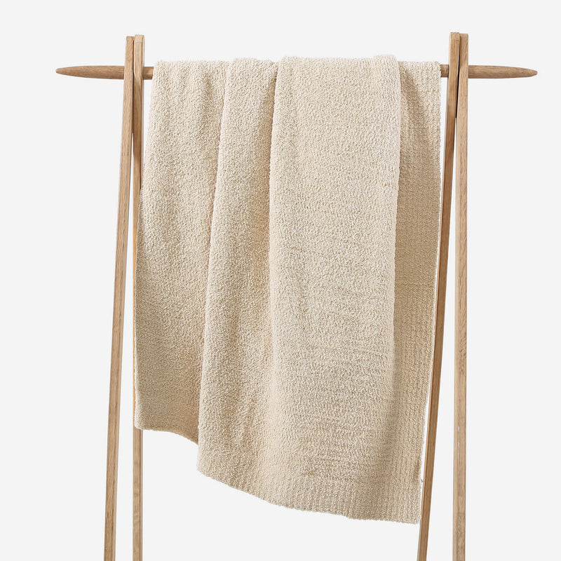 Beige towel hanging on a wooden rack against a white background.