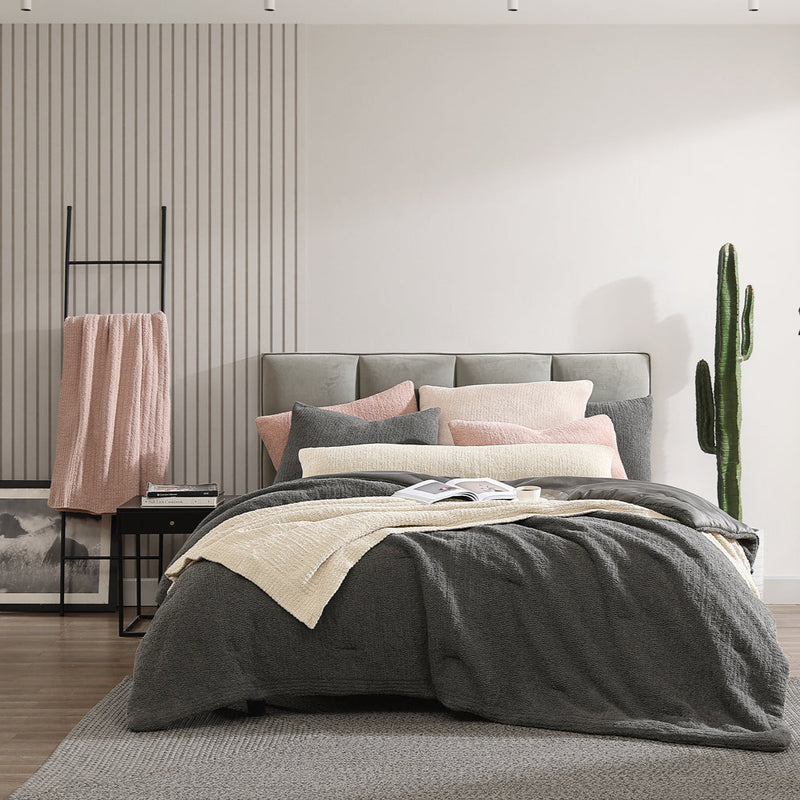 Modern bedroom with cozy bedding, decorative pillows, ladder shelf, and cactus plant.