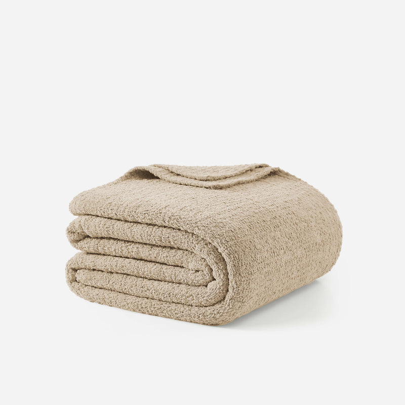 Beige plush bath towel folded neatly on a white background.