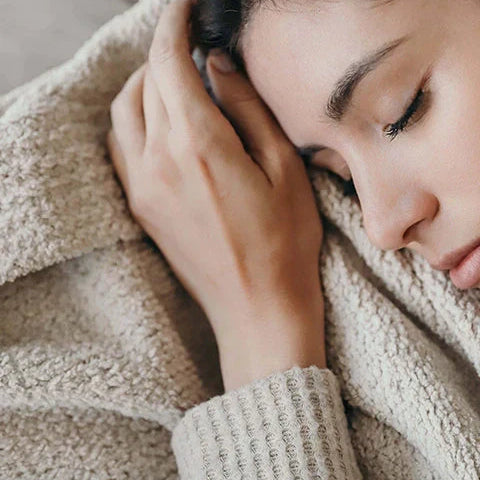 Woman sleeping peacefully wrapped in a cozy beige blanket.
