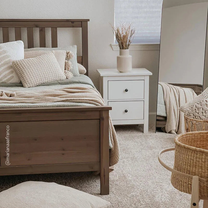 Cozy bedroom with wooden bed frame, white nightstand, neutral-toned bedding, and decorative elements.