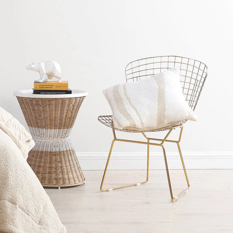 Stylish modern bedroom corner with a wicker side table, decorative bear figurine, and a gold chair with a cozy pillow.