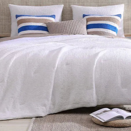 Luxurious white bedspread with decorative pillows in modern bedroom setting.