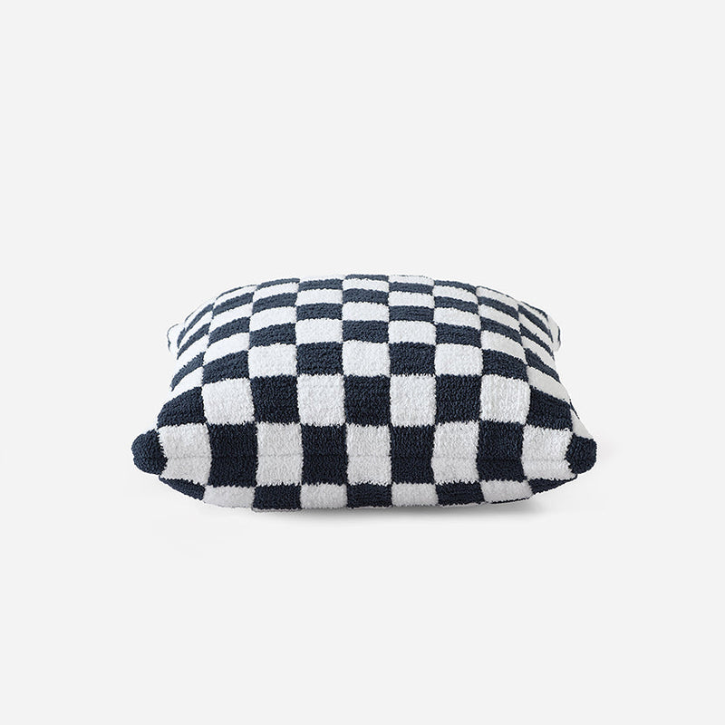 Checkered pattern decorative throw pillow with black and white squares on a white background.