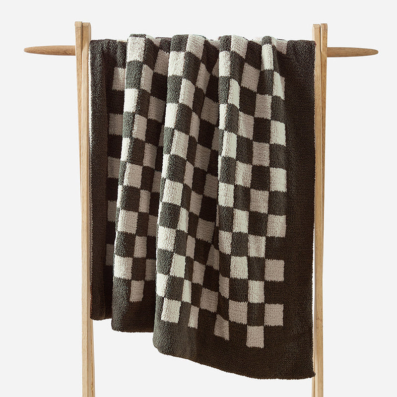Checkerboard pattern blanket on wooden rack, stylish textile home decor.
