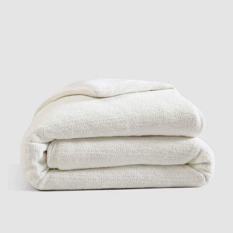 Folded white blanket on a plain gray background, showcasing soft and cozy texture for added comfort.