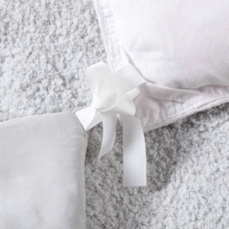 Close-up of gray duvet cover corner with white fabric tie on soft carpet background.
