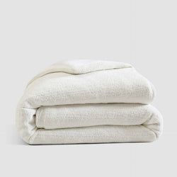 Folded white cotton blanket on a gray background.