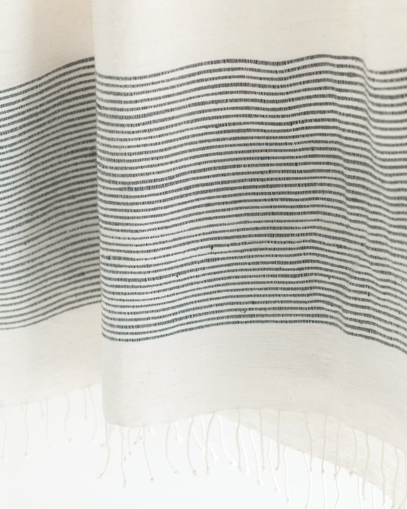 Close-up of white fabric with black horizontal stripes and fringed edge.