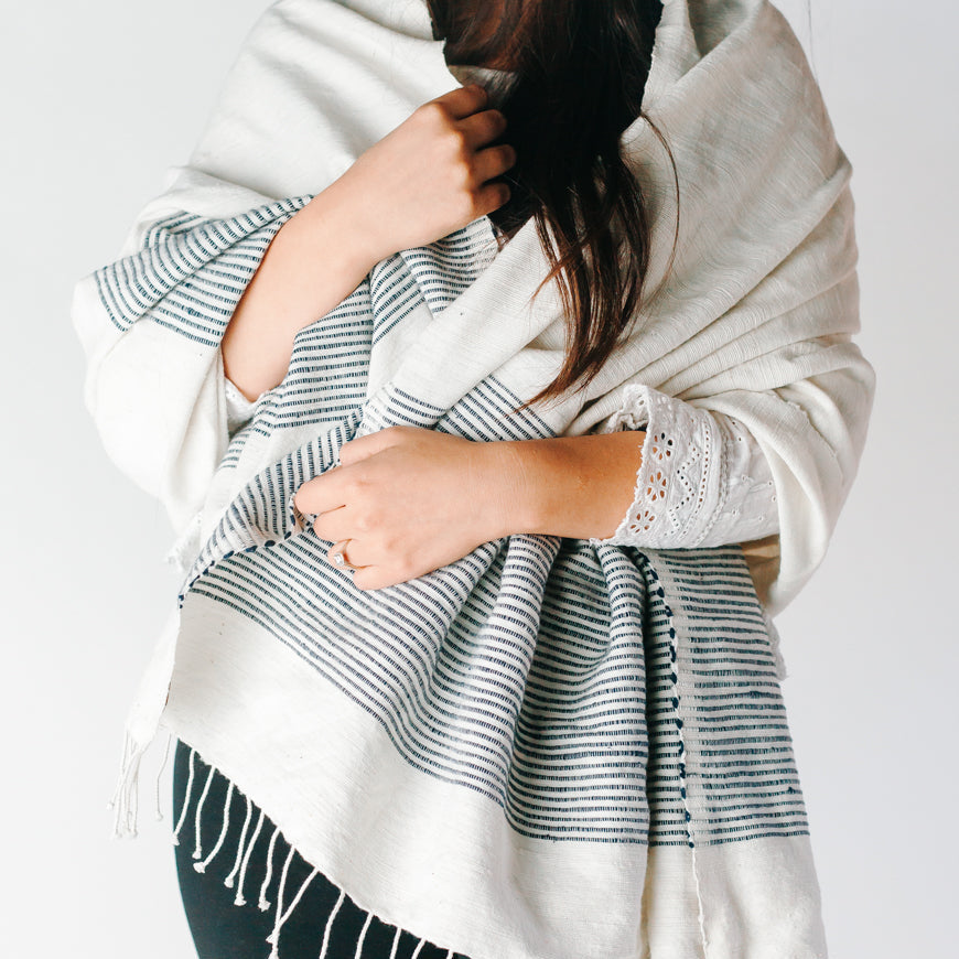 Woman wearing a stylish white and blue striped shawl, showcasing modern fashion and elegance.