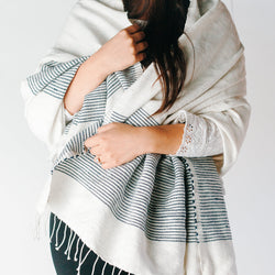 Woman wearing a stylish white and blue striped shawl, showcasing modern fashion and elegance.