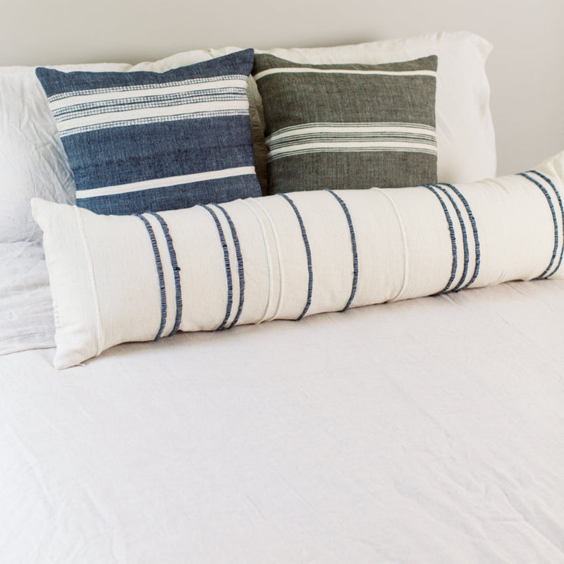 Decorative pillows on a bed with striped cushion design for modern bedroom decor.