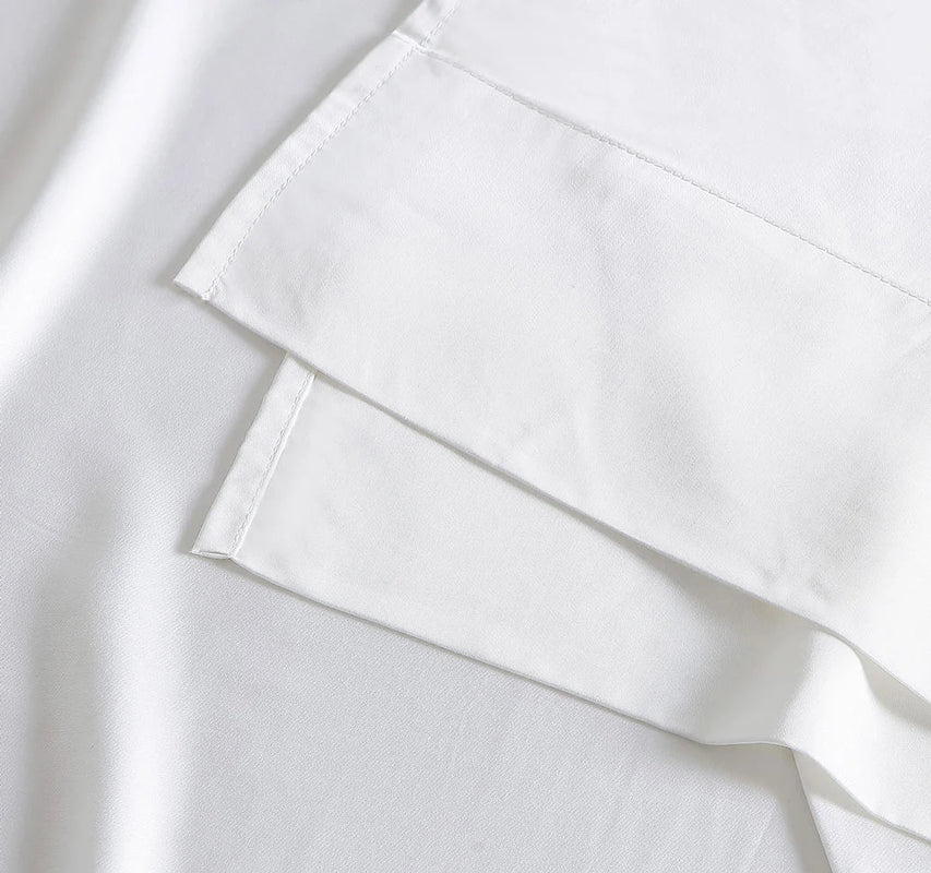 Close-up of a white satin fabric with a luxurious sheen, ideal for bedding or clothing.