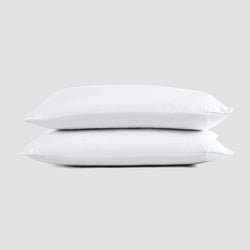 Two stacked white bed pillows on a gray background for bedroom comfort.