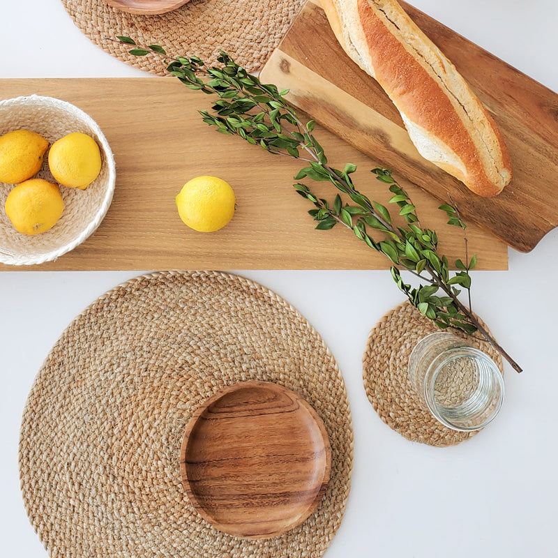 Rustic table setting with fresh lemons, a baguette on a wooden board, and natural woven placemats for a cozy dining experience.