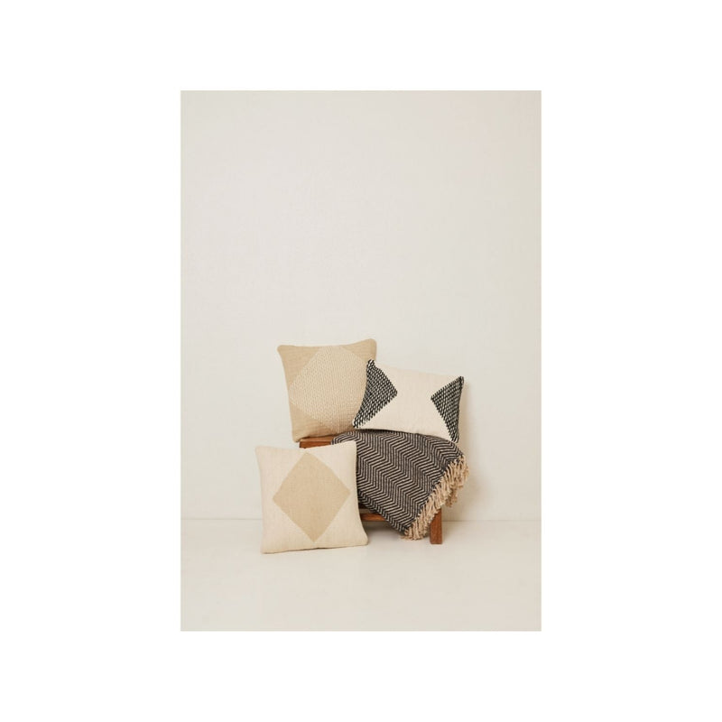 Stylish modern throw pillows with geometric patterns and a fringed blanket for cozy home decor.