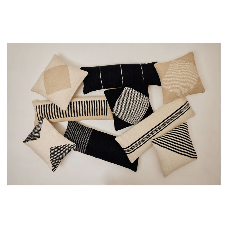 Modern geometric black and beige throw pillows arranged on a neutral background.