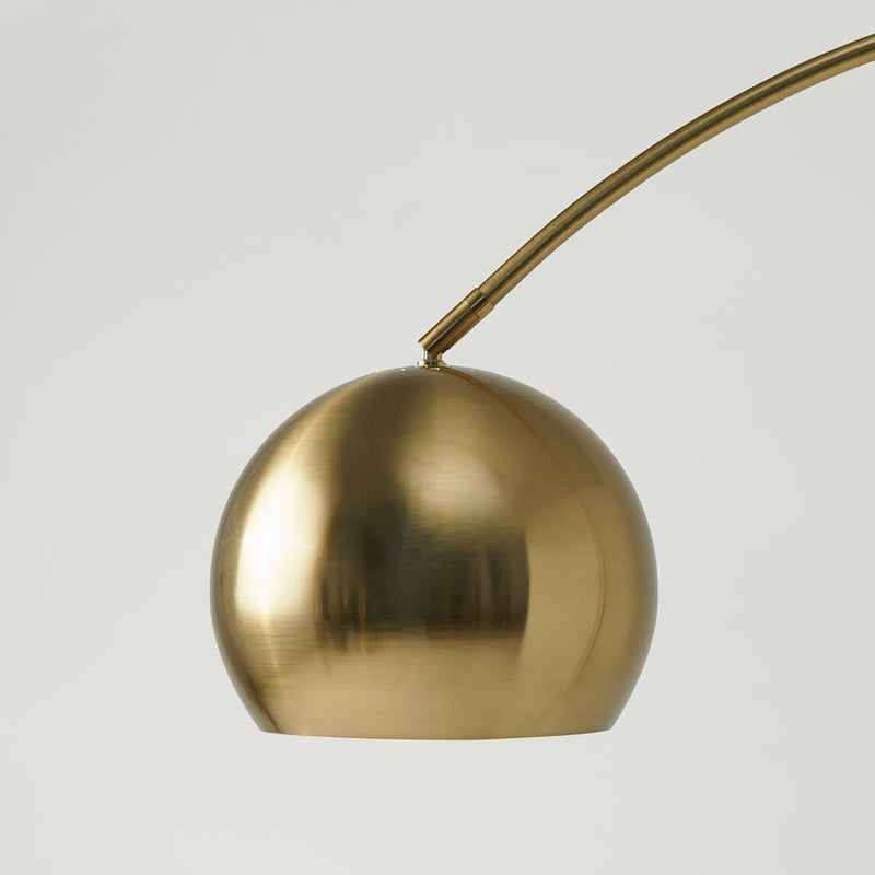 Modern brass arc floor lamp with a sleek spherical shade.