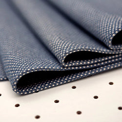 Folded blue houndstooth fabric on white surface with polka dots, ideal for textile projects.