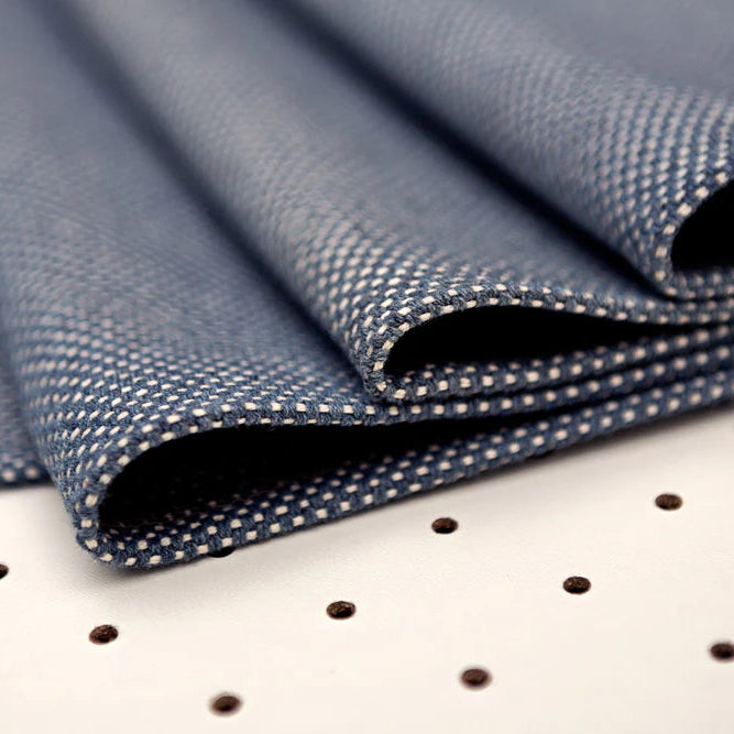 Folded blue houndstooth fabric on white surface with polka dots, ideal for textile projects.