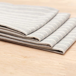 Stack of folded gray striped napkins on a wooden surface.