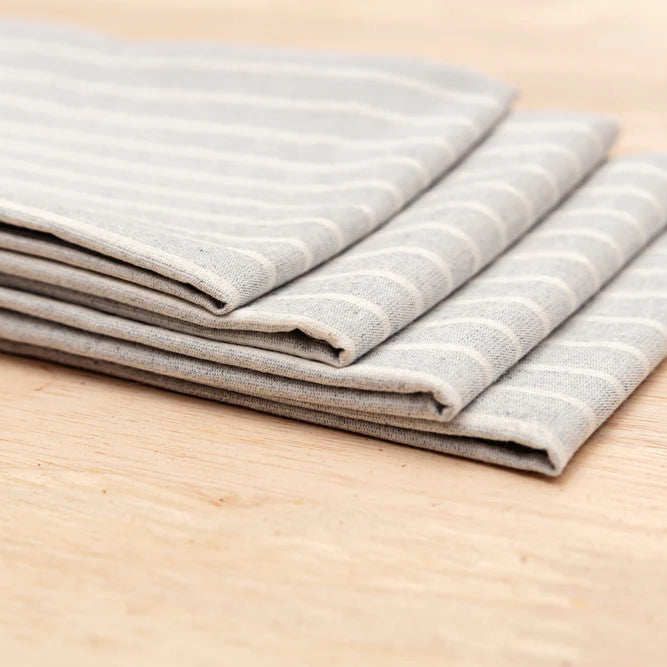 Stack of folded gray striped napkins on a wooden surface.