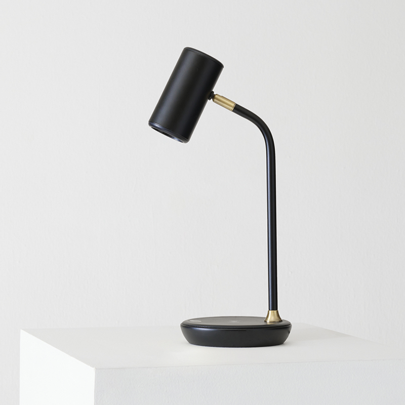 Black modern desk lamp with cylindrical shade on white background.
