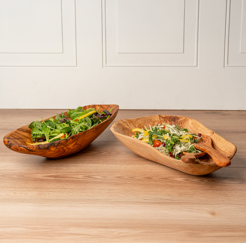 Wooden serving bowls with fresh green salad on a wooden table.