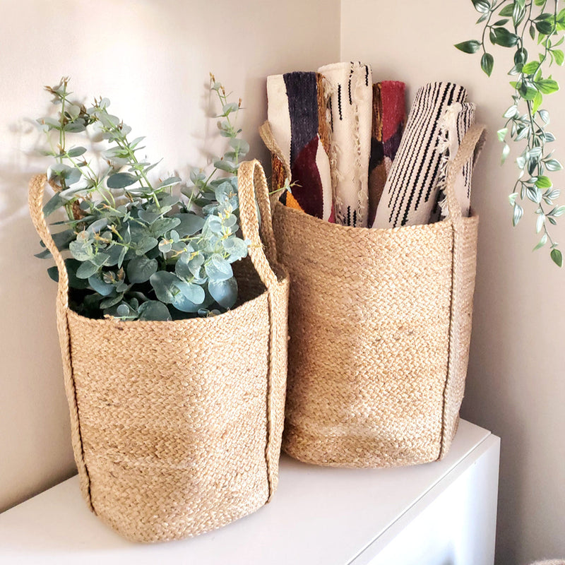 Woven seagrass baskets with lush greenery and rolled textiles for eco-friendly home decor.